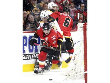 Kris Russell of the Calgary Flames tries to break away from winger Reilly Smith of the Boston Bruins behind the Flames goal during the first period at the Saddledome Monday February 16, 2015.