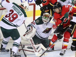 Calgary Flames forward David Jones, right, tries to get a shot into Minnesota Wild netminder Devan Dubnyk as Nate Prosser also defends on Wednesday night. Dubnyk, a Calgarian, made 35 saves as the Wild won 3-2 in overtime.