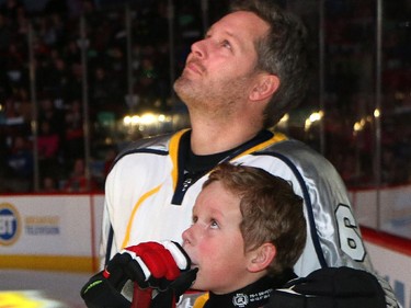 An emotional Rod O'Brien and his son Luke watch a video on the scoreboard showing Luke's brother Nathan before the start of the  Nathan O'Brien Children's Foundation hockey game Thursday February 5, 2015 at the Saddledome.