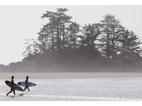 Surfers make their way into the Pacific Ocean at Tofino Vancouver Island, where you could also ski on the same day in the winter.