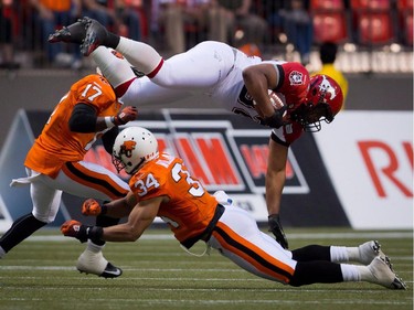 Calgary Stampeders' Nik Lewis, top, is upended by B.C. Lions' Torri Williams after catching a pass during the first half of a pre-season CFL football game in Vancouver, B.C., on Friday June 20, 2014.