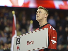 Calgary Stampeders quarterback Bo Levi Mitchell holds Team Alberta's placard before Draw 10, which featured the Battle of Alberta between John Morris and Kevin Koe, at the Scotiabank Saddledome on Tuesday night at the Brier.