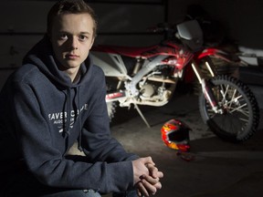 Matthew Foster, a motocross rider, poses with the bike and broken helmet he was using when he suffered a concussion, in Calgary, on March 4, 2015.