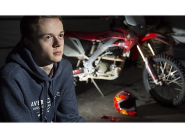 Matthew Foster, a motocross rider, poses with the bike and broken helmet he was using when he suffered a concussion, in Calgary, on March 4, 2015.