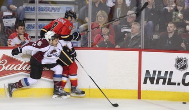 ]Colorado Avalanche defenceman Zach Redmond, left, drives Calgary Flames centre Joe Colborne into the boards at the Scotiabank Saddledome in Calgary on Monday, March 23, 2015. The Calgary Flames lead the Colorado Avalanche, 2-1, at the end of the second period in regular season NHL play.