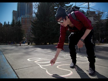 Colin Bullshields chalks a protest against the proposed antiterrorism bill C-51 outside Eau Claire Market in Calgary on Friday, March 27, 2015.