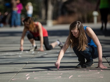 Protestors of the proposed antiterrorism bill C-51 create chalk art protest slogans along the Eau Claire pathway in Calgary on Friday, March 27, 2015.