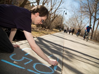 Jacob Longbotham writes "stop C-51" on the Prince's Island pathway as part of his protest against proposed anti-terrorism legislation in Calgary on Friday, March 27, 2015.