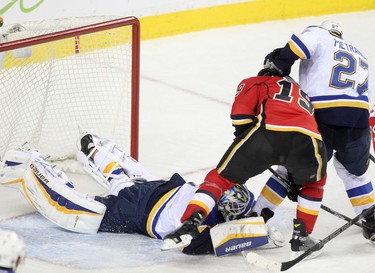 Calgary Flames David Jones, middle, tries to sore on St. Louis Blues Brian Elliott during their game at the Scotiabank Saddledome.