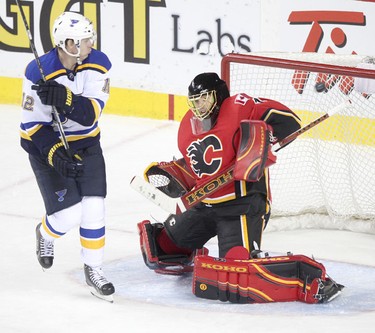 Flames goalie Jonas Hiller tries to stop a shot as St. Louis Blues Jori Lehtera watches during their game at the Scotiabank Saddledome.