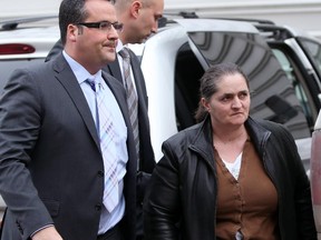 Rodica Radita, right, is taken into custody by police in Calgary on February 18, 2014.