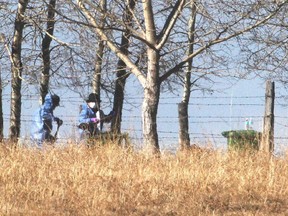Police in hazmat suits and using shovels continue the renewed search of the farm of Doulgas Garland and his parents Monday March 30, 2015.