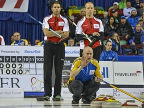 Team Canada's John Morris, left, and Pat Simmons, who took over as skip in a dramatic team switch earlier in the day, watch as Team Alberta skip Kevin Koe directs the sweepers in the Tuesday evening draw at the Tim Hortons Brier. Morris won 6-3.