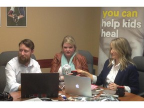 Michael Lang, left, Laura Cuthbertson and Dr. Catherine Laing review the photos that have been submitted for Cuthbertson's digital story at the Kids Cancer Care offices in Calgary on March 26, 2015.