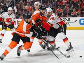 Calgary Flames defenceman Deryk Engelland, right, battles with Philadelphia's Matt Read, left, and Sean Couturier for a loose puck on Tuesday night. It was the best effort of the season from the rugged rearguard, who stepped up in Mark Giordano's absence.