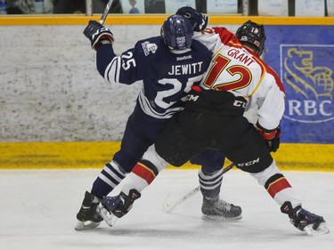 Mount Royal Cougars' Tyler Jewitt takes a shove back from University of Calgary Dinos' Colton Grant during CIS playoff action at Father David Bauer arena in Calgary, on March 1, 2015.