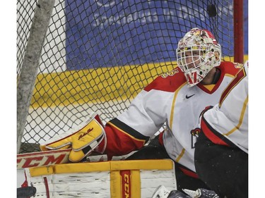 University of Calgary Dinos' goalie Kris Lazaruk keeps his eye on the puck during CIS playoff action against the Mount Royal Cougars at Father David Bauer arena in Calgary, on March 1, 2015.