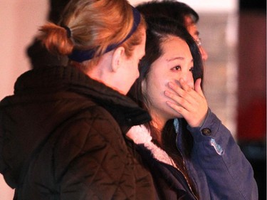 A woman identified as a resident, right, watched as member of the Calgary Fire Department worked to ensure the flames were extinguished after a two alarm fire at 250 Everridge Drive SW on March 10, 2015.