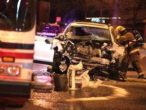 Calgary firefighters work to douse the smouldering engine of an SUV that was involved in a collision with a Calgary Transit bus at the intersection of Willow Park Drive and Macleod Trail on March 22, 2015.