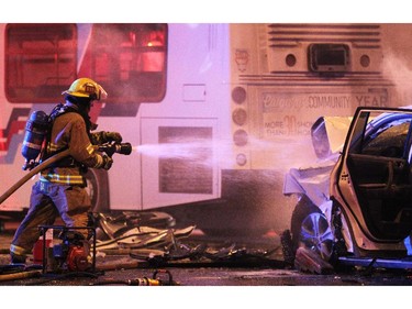Calgary fire fighters worked to dowse the smouldering engine of an SUV which was involved in a collision with a Calgary Transit bus at the intersection of Willow Park Drive and Macleod Trail SW on March 22, 2015.