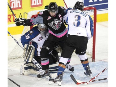 Calgary Hitmen left winger Kenton Helgesen and Kootenay Ice defenceman Tanner Lishchynsky, right, got tangled up with each other in the crease of Kootenay Ice goalie Wyatt Hoflin during first period WHL action at the Scotiabank Saddledome on March 22, 2015.
