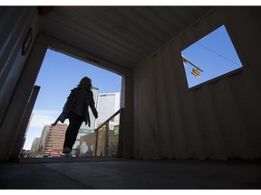 A woman enters a metal container tunnel built for pedestrians to allow safe sidewalk passage next to the elaborate construction site on 10 Avenue and 8 Street S.W in Calgary, on February 23, 2015.