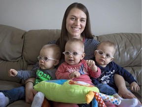 Leslie Low holds her triplets, who were all diagnosed with a rare eye cancer.