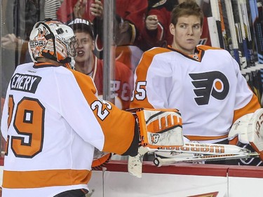 Philadelphia Flyers goalie Steve Mason, right, who was pulled in the middle of the second period, takes replacement goalie Ray Emery's broken stick, which he smashed in half after getting a penalty for slashing, during a game against the Flames at the Saddledome in Calgary, on March 19, 2015.