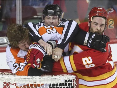 Calgary Flames Deryk Engelland takes a job from Philadelphia Flyers Ryan White during NHL action at the Saddledome in Calgary, on March 19, 2015.