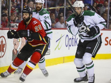 Calgary Flames Brandon Bollig races for the puck behind the Dallas Stars' net with Jordie Benn, right, and Jason Demers close behind during game action at the Saddledome in Calgary, on March 25, 2015.