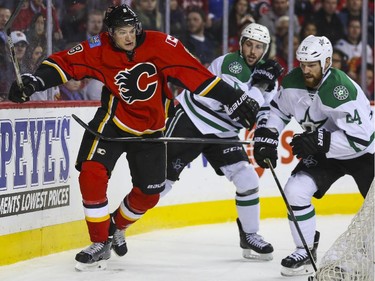 Calgary Flames Joe Colborne is chased down behind the Dallas Stars' net by Jordie Benn, right, and Jason Demers during game action at the Saddledome in Calgary, on March 25, 2015.