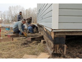 HIGH RIVER, ; MARCH 30, 2015  -- Mike Ferguson places a support beam under the Little Bow School house in the Sheppard Family Park as they prepare to move it. As the Town of High River continues to heal from the 2013 Flood one big park project was worked on on March 27th. The Little Bow School built over 100 years ago floated up in the water with its temporary foundation, turned 180 degrees before crashing into a tree where it then settled, almost perfectly level, and sat for two years. Holmes building movers spent the day moving it around to face the right direction on its new foundation. (Lorraine Hjalte/Calgary Herald) For News story by . Trax # 00063785A