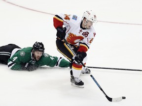 Calgary Flames' Jiri Hudler (24) of the Czech Republic handles the puck under pressure from Dallas Stars' Jason Demers (4) in the third period of an NHL hockey game Monday, March 30, 2015, in Dallas. The Flames won 5-3.