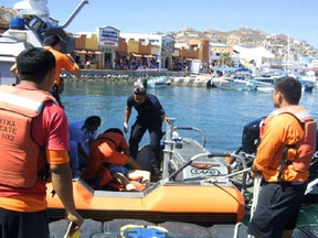 People provide help to a woman on a boat after an incident with a whale  in  Mexico on Thursday, March 12, 2015. Mexican authorities said that a 35-year-old Canadian woman has died and two other tourists were injured near a beach resort when a surfacing  whale crashed onto their boat as they came back from a snorkel tour.