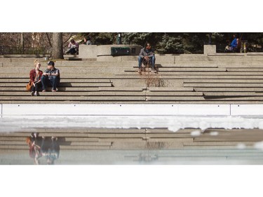 Calgarians enjoy the warm weather at Olympic Plaza on Thursday, March 19, 2015.  The ice rink is rapidly melting in the above-seasonal temperatures.