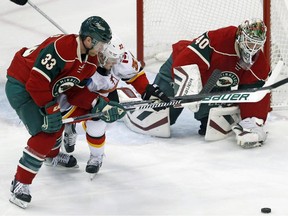 Minnesota Wild's Jordan Leopold, left, tries to keep Calgary Flames' Paul Byron from the rebound of a blocked shot by goalie Devan Dubnyk on Friday.