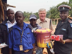 Paul Carrick (light brown shirt, sandals) distributes hand-washing stations in West Africa to prevent Ebola spread.