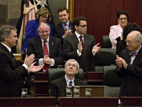 Alberta Premier Jim Prentice, left, and Minister of Health Stephen Mandel, right, applaud Alberta Finance Minister Robin Campbell after he delivered the 2015 budget in Edmonton on Thursday, March 26, 2015.