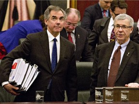Alberta Premier Jim Prentice, left, carries the budget after Alberta Finance Minister Robin Campbell, right, delivered the 2015 budget in Edmonton, Alta., on Thursday, March 26, 2015.