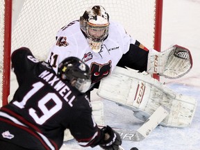Calgary Hitmen goalie Mack Shields, right, blocks a shot from Red Deer Rebels' Brooks Maxwell during their game at the Scotiabank Saddledome  on Wednesday night.