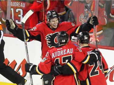 Calgary Flames centre Sean Monahan, top, celebrated with teammates left winger Johnny Gaudreau and centre Jiri Hudler after scoring the Flames first goal of the game against the Columbus Blue Jackets during first period NHL action at the Scotiabank Saddledome on March 21, 2015.