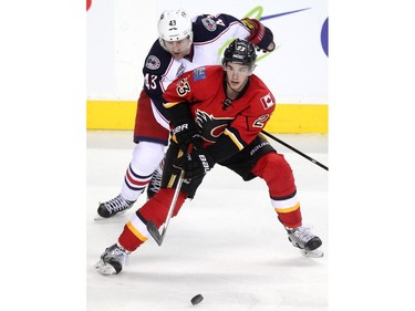 Calgary Flames centre Sean Monahan passed the puck while being pressured by Columbus Blue Jackets left winger Scott Hartnell during second period NHL action at the Scotiabank Saddledome on March 21, 2015.