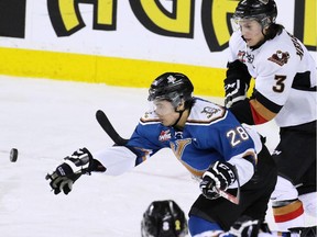 Calgary Hitmen Kenton Helgesen and the Kootenay Ice's Lenny Hackman chase the puck in the second period against the Kootenay Ice. The game was the first in a best-of-seven WHL playoff series against the Ice on Friday March 27, 2015.