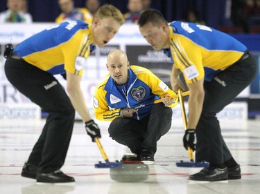 Alberta skip Kevin Koe kept an eye on his shot as third Marc Kennedy and lead Ben Hebert slid with it down the sheet against Saskatchewan during the afternoon draw at the Tim Hortons Brier at the Scotiabank Saddledome in Calgary on March 5, 2015.