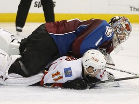 Colorado Avalanche goalie Semyon Varlamov, of Russia, lands on Calgary Flames center Mikael Backlund, of Sweden, during the second period of an NHL hockey game Saturday, March 14, 2015, in Denver.