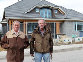 Doug King, left, and Kevin Graham are wondering if the City of Calgary has a way to get a home that has been under construction for 11 years finished, at 92 Spring Valley Way S.W. in Springbank Hill.