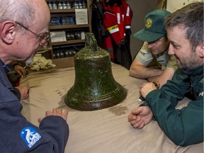 Dr. Douglas Stenton (from left), Ryan Harris and Jonathan Moore examine the ship's bell from the Erebus.