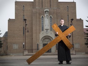 Deacon Adrian Martens with the Roman Catholic Dioceses of Calgary, holds the oversized cross used during Good Friday's Way of the Cross celebration in Calgary.