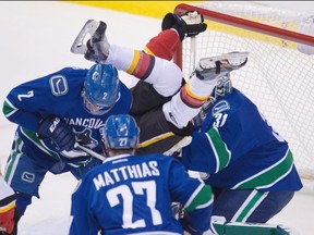 Calgary Flames centre Sam Bennett (63) goes head over heels as he tries to get a shot past Vancouver Canucks goalie Eddie Lack (31) as Vancouver Canucks centre Shawn Matthias (27) and Vancouver Canucks defenceman Dan Hamhuis (2) look on.
