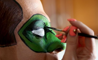 Makeup artist Lianne Moseley paints model Ken Dove into DC Comic character Green Lantern.